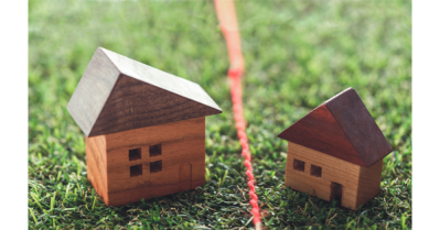 Boundary Survey Cost: Land Surveyor for Boundaries from SAM Conveyancing. Two wooden block toy houses are separated by a red line on the ground.