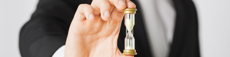 Top Tips for buying a flat with a short lease, from SAM Conveyancing: a Caucasian person in a formal suit holds an hour glass up, filling the frame