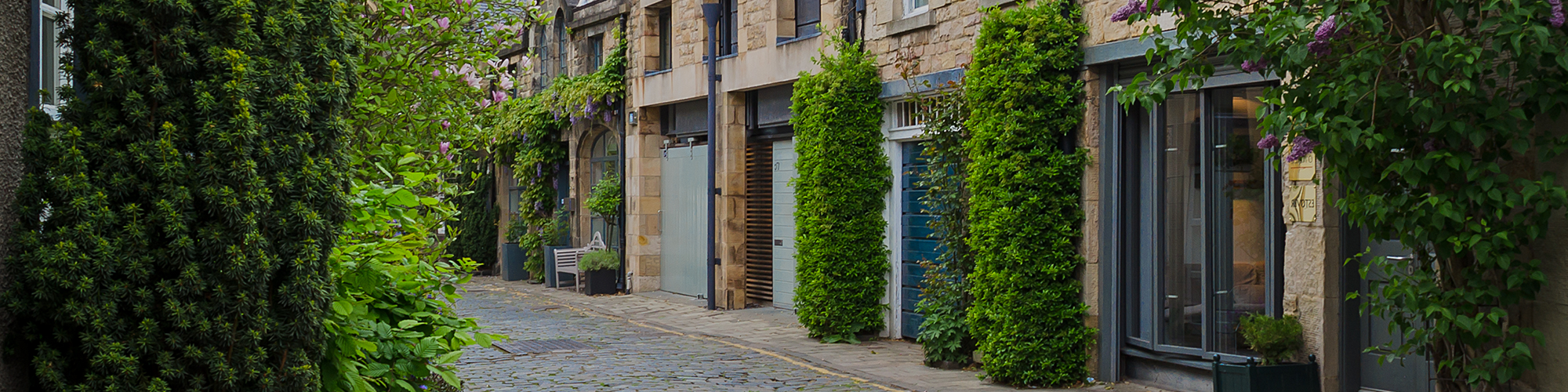 A leafy cobbled residential street, of converted garages. SAM Conveyancing discussed the risks of buying a house with a garage conversion without building regulations, and how to resolve them.