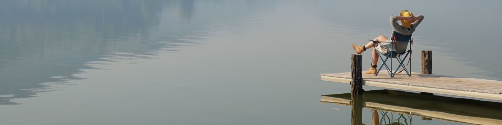 A woman relaxes in a camping chair overlooking a peaceful lake, enjoying easy conveyancing from SAM Conveyancing