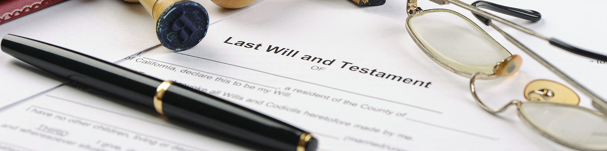 Stamps, pen and glasses sitting on top of a will. SAM Conveyancing's guide on how to apply for grant of probate