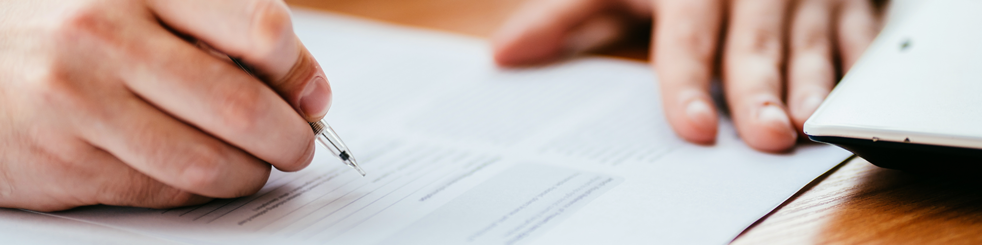 Man in a suit signing a form in an office. Landlord Statutory Declaration. A guide from SAM Conveyancing on how to file a statutory declaration form