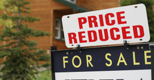A bright summer day showing a reduced price estate agent sign, reflecting the August 2026 UK housing market slowdown