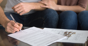 A couple sign their paperwork for Buying a Flat With Section 20 Notice. SAM Conveyancing explains the implications