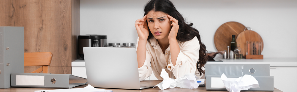 A woman working from her kitchen with a laptop getting frustrated over delays with legal enquiries