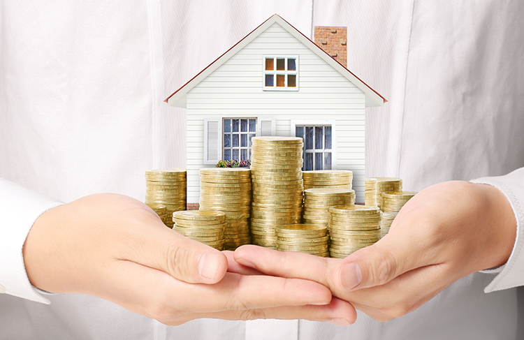 How to Sell Your House from SAM Conveyancing: A man in a white shirt cups a model house and a stack of coins in his hands, in front of his chest.