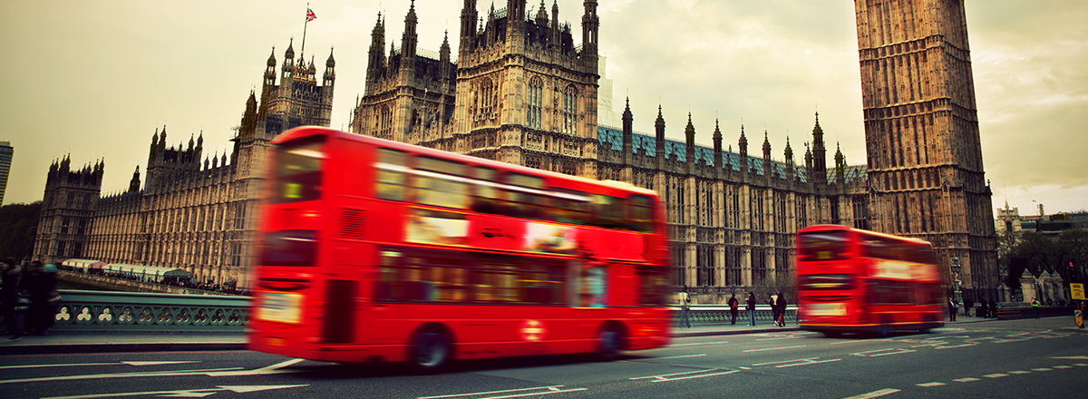 Two red London buses drive past the Palace of Westminster and Big Ben, SAM Conveyancing discuss the London Housing Market