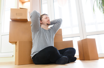 Picture of a relaxed man next to boxes having moved in after fast solution conveyancing