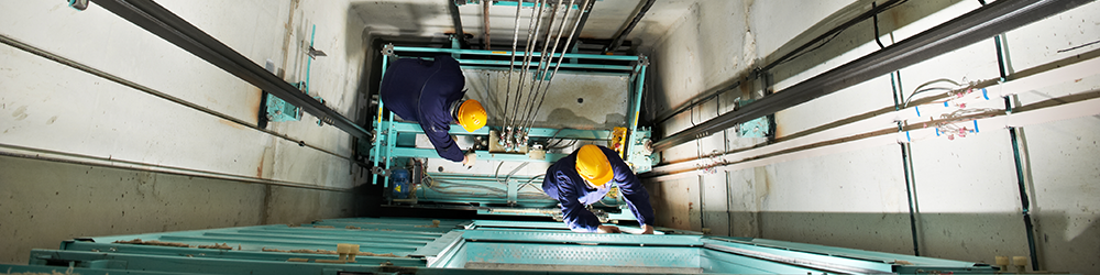 Section 20 Major Works. SAM Conveyancing breaks down leasehold major works payments, otherwise known as 'qualifying works'. Two workers in hard hats and boiler suits are in a lift shaft, repairing the lift.