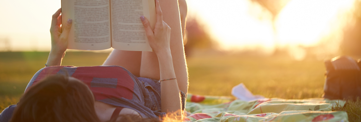 Woman reading a book in her garden enjoying the summer sunshine
